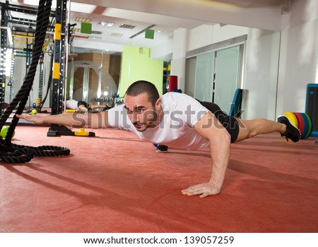 Crossfit fitness man balance push ups with one leg and arm up exercise at gym workout