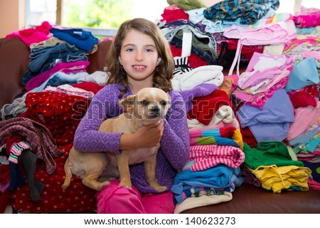 girl sitting on a messy clothes sofa with chihuahua dog before folding laundry