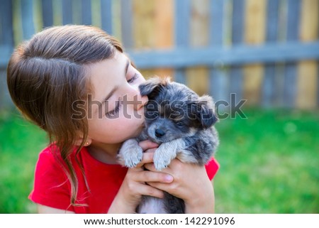 children girl kissing her puppy chihuahua doggy on the wood fence