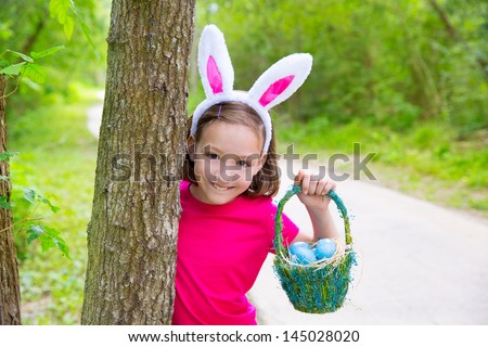 Easter girl with eggs basket and funny bunny face expression at the forest