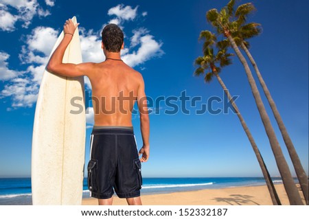 Boy surfer back rear view holding surfboard on California palm trees beach [ photo-illustration]