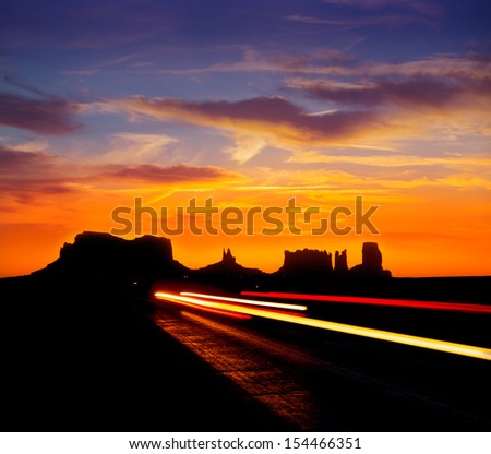 Sunrise on US 163 Scenic road to Monument Valley Park with car headlights Utah