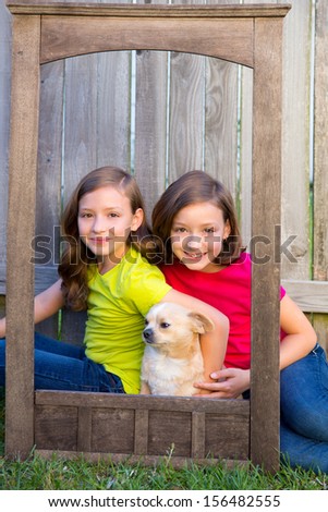 Twin sisters portrait with chihuahua dog on grunge wood border frame sitting on lawn