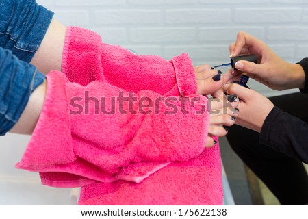 Pedicure chair spa and woman hands painting toes nail polish after bath with pink towel