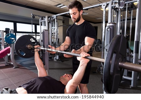 Bench press weightlifting man with personal trainer in fitness gym