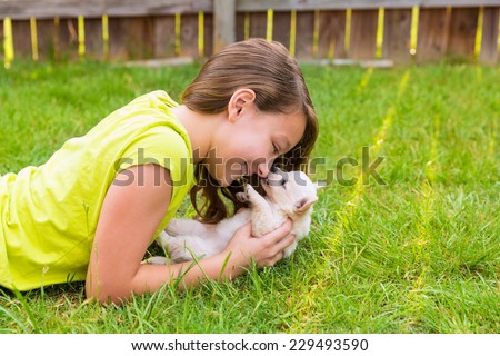 kid girl and puppy dog happy playing with chihuahua  pet lying in backyard lawn