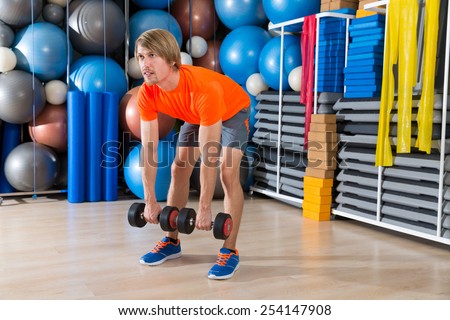 dumbbell deadlift blond man at gym weightlifting with swiss ball background
