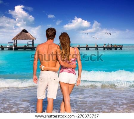 Couple of young tourists in a tropical summer beach rear view hug