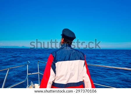rear sailor man sailing sea ocean in a boat with captain cap looking horizon