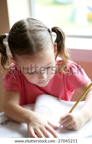 Little toddler girl writing at school desk, homework