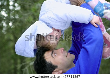 Father winter turning upside down his daughter, laughing outdoors