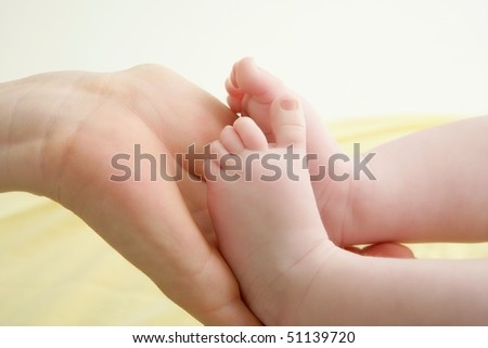 baby feet in mother hands playing together