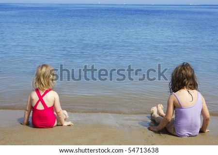 tow sisters sit on beach bathing suit swimsuit back view summer vacation
