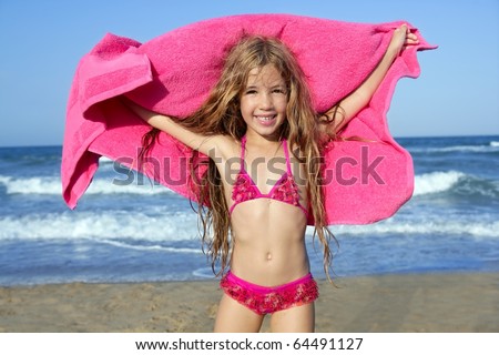 Beach little girl playing pink towel and wind in blue sea