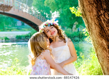 kid girls playing in spring outdoor river park whispering ear