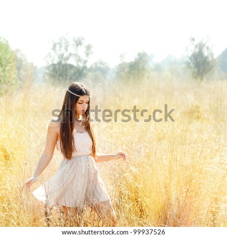 Asian indian woman walking in golden dried grass field