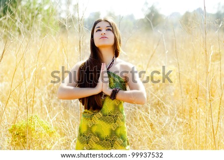 Asian indian woman praying hands  in golden field with green dress