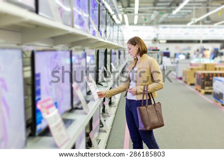 woman l looks at LCD TVs in supermarket