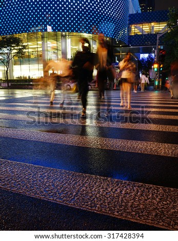 Night view of Crosswalk and pedestrian at modern city zebra crossing street in rainy day. Light trails and Blur abstract.