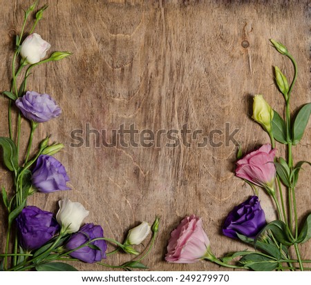 beautiful eustoma flowers with leafs and buds on wooden background. photo frame, collage