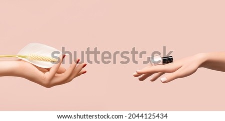 Female hand with glitter red nail design. Female hand hold white Spathiphyllum flower. Woman hand on pink background. Glitter red nail polish manicure. Female hand hold pink nail polish bottle.