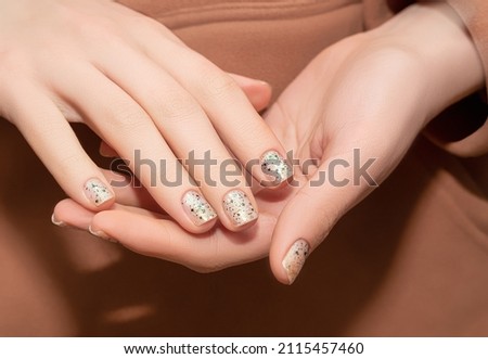 Female model hands with clear nail design. Glitter clear nail polish manicure with green nail art. Female model with perfect manicure in brown hoodie 商業照片 © 
