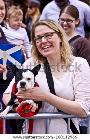 NEW YORK - APRIL 14:  A woman poses with her dog as she watches the Scotland Week Parade on 6th Avenue April 14, 2011 in New York, NY.