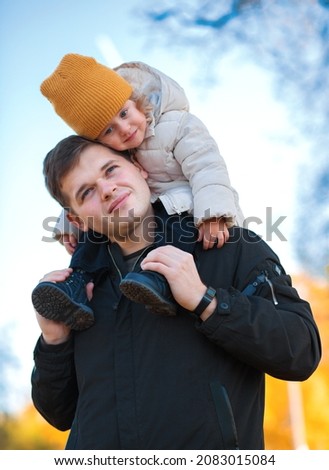Father gives his son a ride on his back in the park. Portrait of a pensive father giving his daughter a piggyback ride on his shoulders and looking up. Cute baby girl with her father Photo stock © 