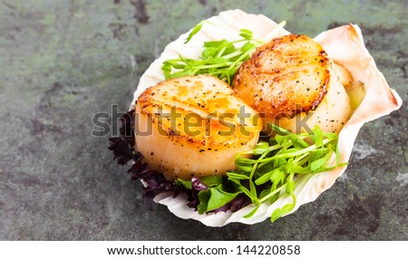 Pan seared scallops with garnish on a stone plate..