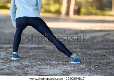 Foto Bild Nicht erkennbare Sportlerin, die im Freien die Arme streckt.