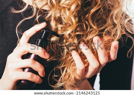 Close-up young woman applying cosmetic treatment oil to her curly hair to prevent split ends Foto stock © 