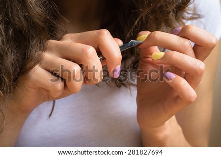 Care for cuticles with manicure scissors. Female hands with a bright manicure keep cosmetic tool closeup.