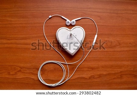 A white headphones connected to white polymer clay heart on the wood background. Happy life. Happy lifestyle. Good life. Life is good. Music and joy. Music concept. Love music.
