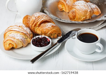 Croissants with jam and coffee on wooden table still life