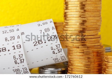 Cash register paper receipt check with coins stack closeup
