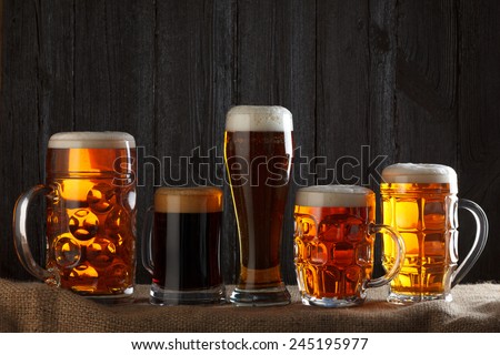 Beer glasses with lager, dark lager, brown ale, malt and stout beer on table, dark wooden background