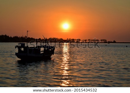 Photo of a small fishing boat is anchored in a calm sea, with a beautiful sunset and an orange sky. Taken at Losari Beach, Makassar.  Stok fotoğraf © 