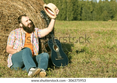 man with guitar and beer on the nature