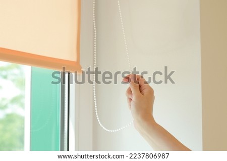 Woman's hand lowers or raises roller blinds in her office Foto stock © 