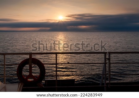 Dawn on the sea. Ship lifebuoy with the sun about to sink below the horizon.