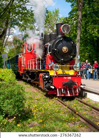 KIEV, UKRAINE - MAY 9: Steam locomotive of old Toy Train can be seen in the station in Kyiv at May 9, 2015. Parents with children on the platform in the background.