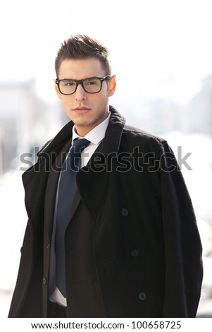 Businessman wearing suit , coat and glasses, looking to the camera - outdoor picture