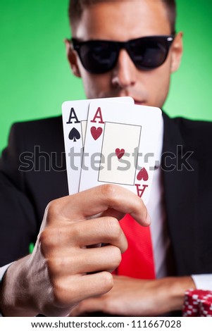 Young business man showing you his pair of aces, on green background