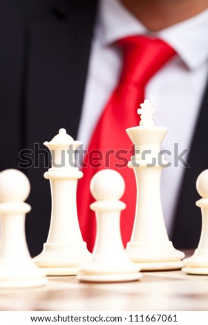 White chess king, queen and pawns in front of business man