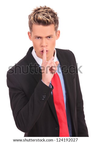 Portrait of business man showing silence gesture with his forefinger by mouth