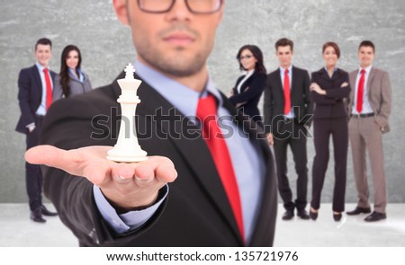 young business man leader of a successful business team holding the white king of chess on the top of his hand