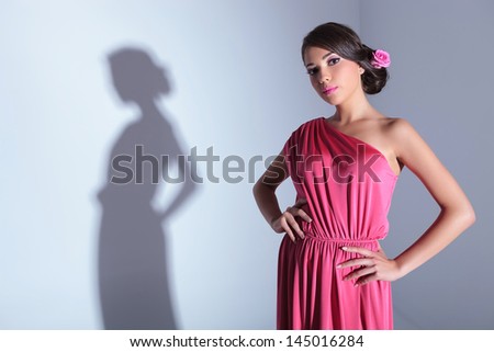 young beauty woman with hands on hips is looking at the camera. on a light gray background with shadow