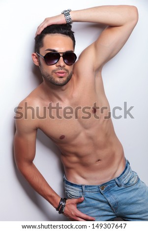 young topless man pulling his hair back while looking at the camera. on light gray background