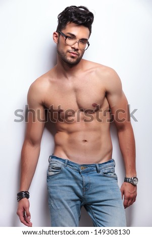 young topless man with eyeglasses looking at the camera. on light gray background