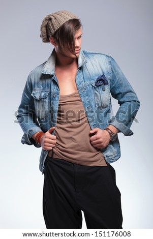 casual young man looking down while holding his hands on his jacket. on gray studio background